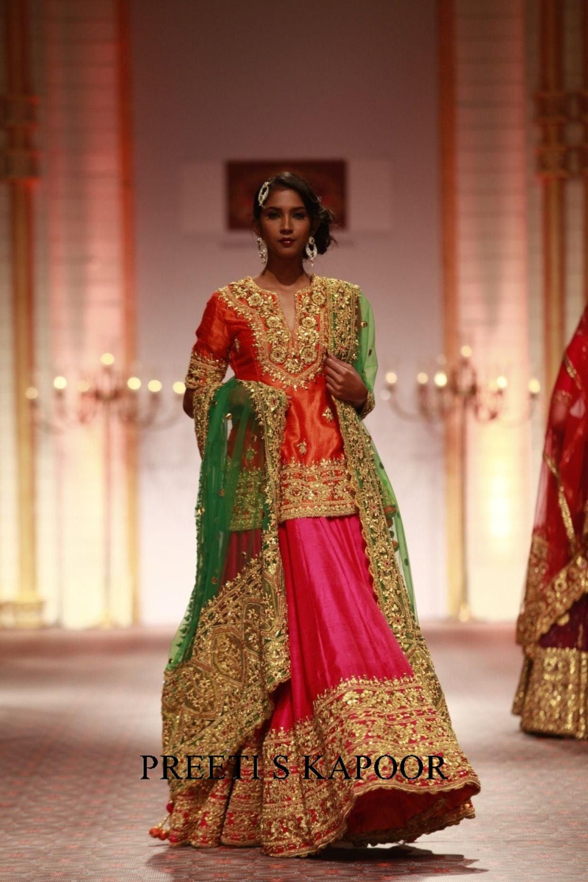 Model wearing a traditional outfit with intricate designs on a runway, branded 'Preeti S Kapoor'.