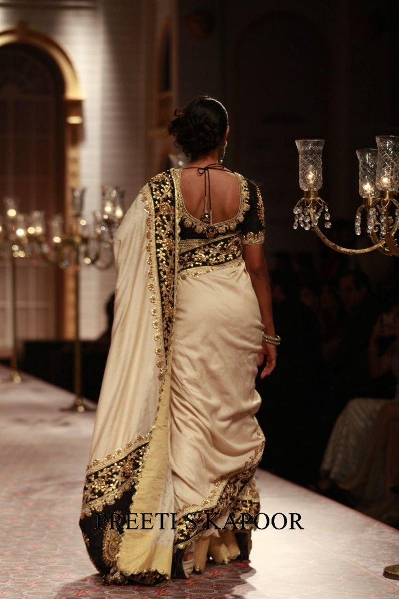 Woman in a saree walking on a runway with chandeliers in the background