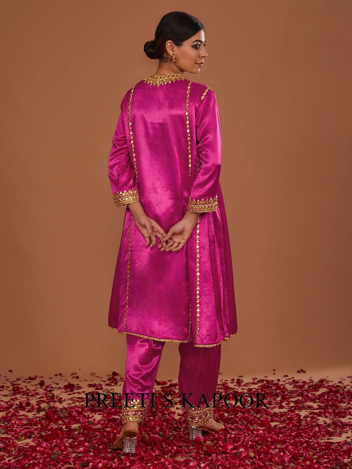 Woman in a pink traditional outfit with gold embroidery on a brown background