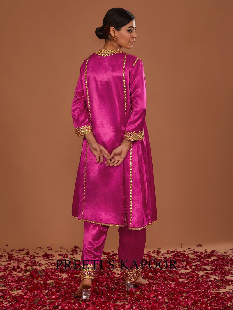 Woman in a pink traditional outfit with gold embroidery on a brown background
