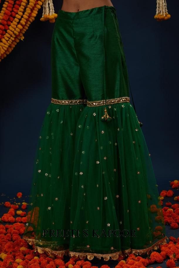 Green traditional outfit with intricate patterns on a dark background