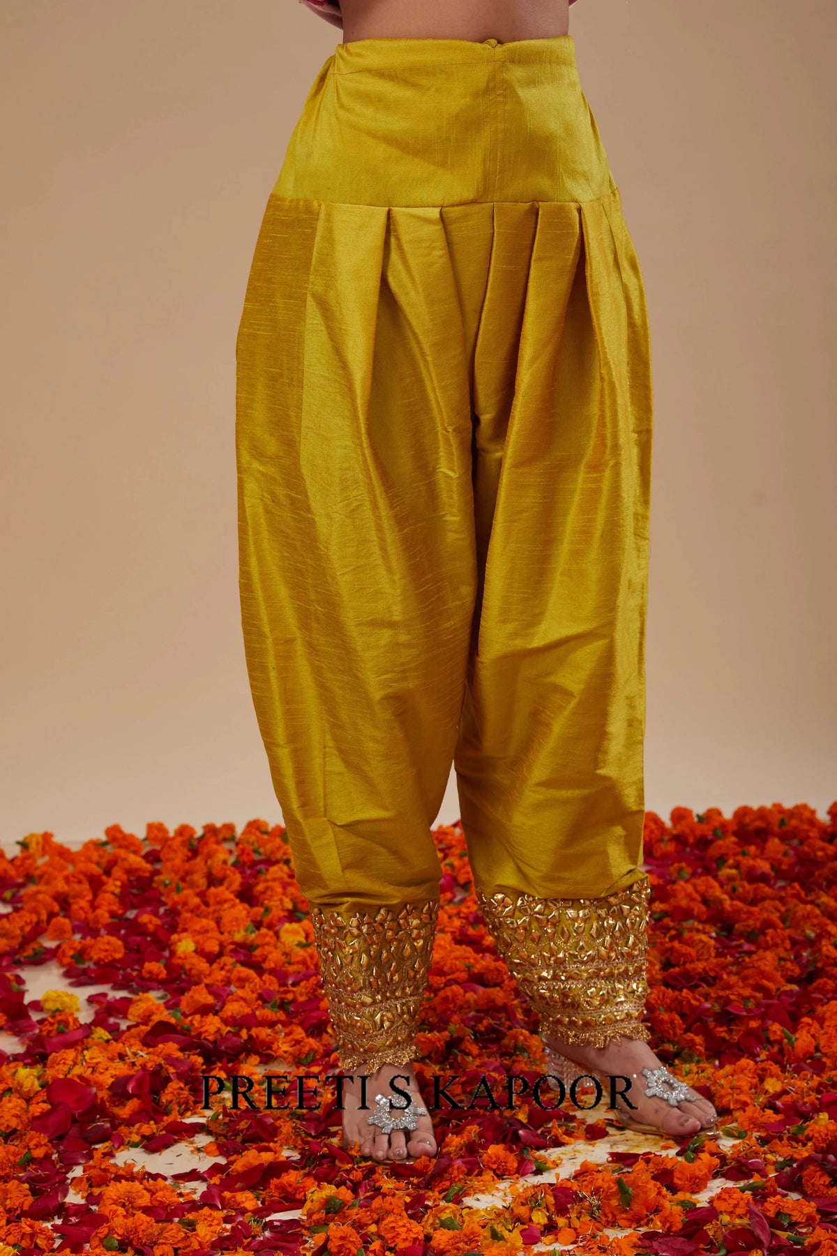 Yellow traditional pants with gold hem on a floral background - Preeti S Kapoor