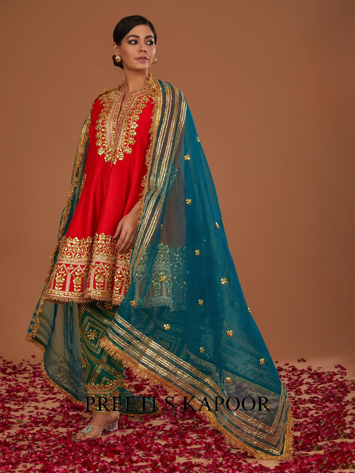 Woman in a red and blue traditional outfit with gold embroidery on a brown background