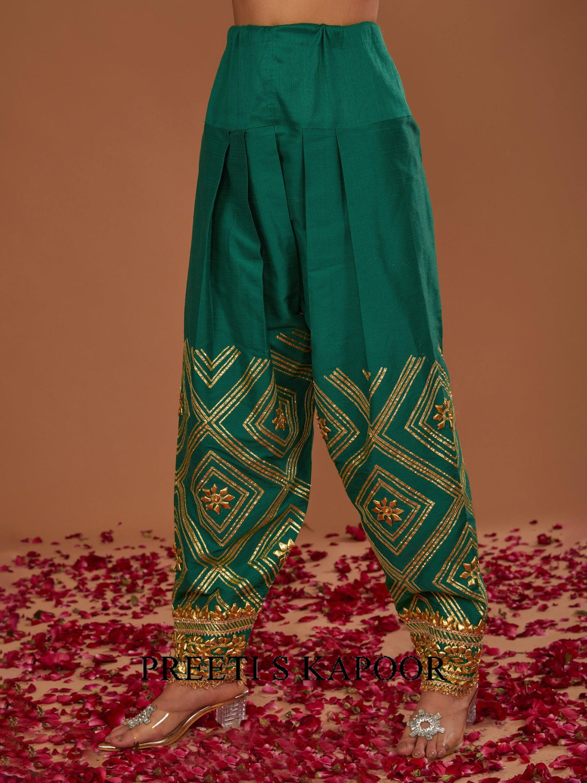 Green embroidered pants on a model with a brown background