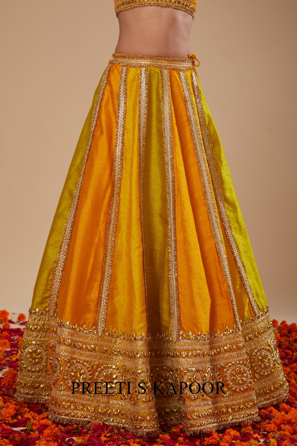 Yellow and orange traditional outfit with intricate designs on a beige background