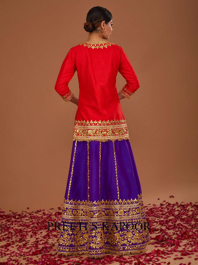 Red and purple traditional outfit with gold embroidery on a brown background
