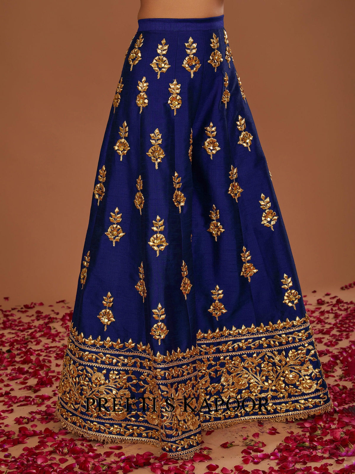 Blue embroidered lehenga with gold details on a brown background