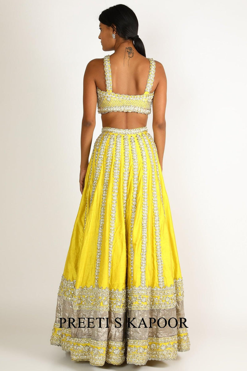 Woman wearing a yellow and white traditional outfit with 'Preeti S Kapoor' branding.