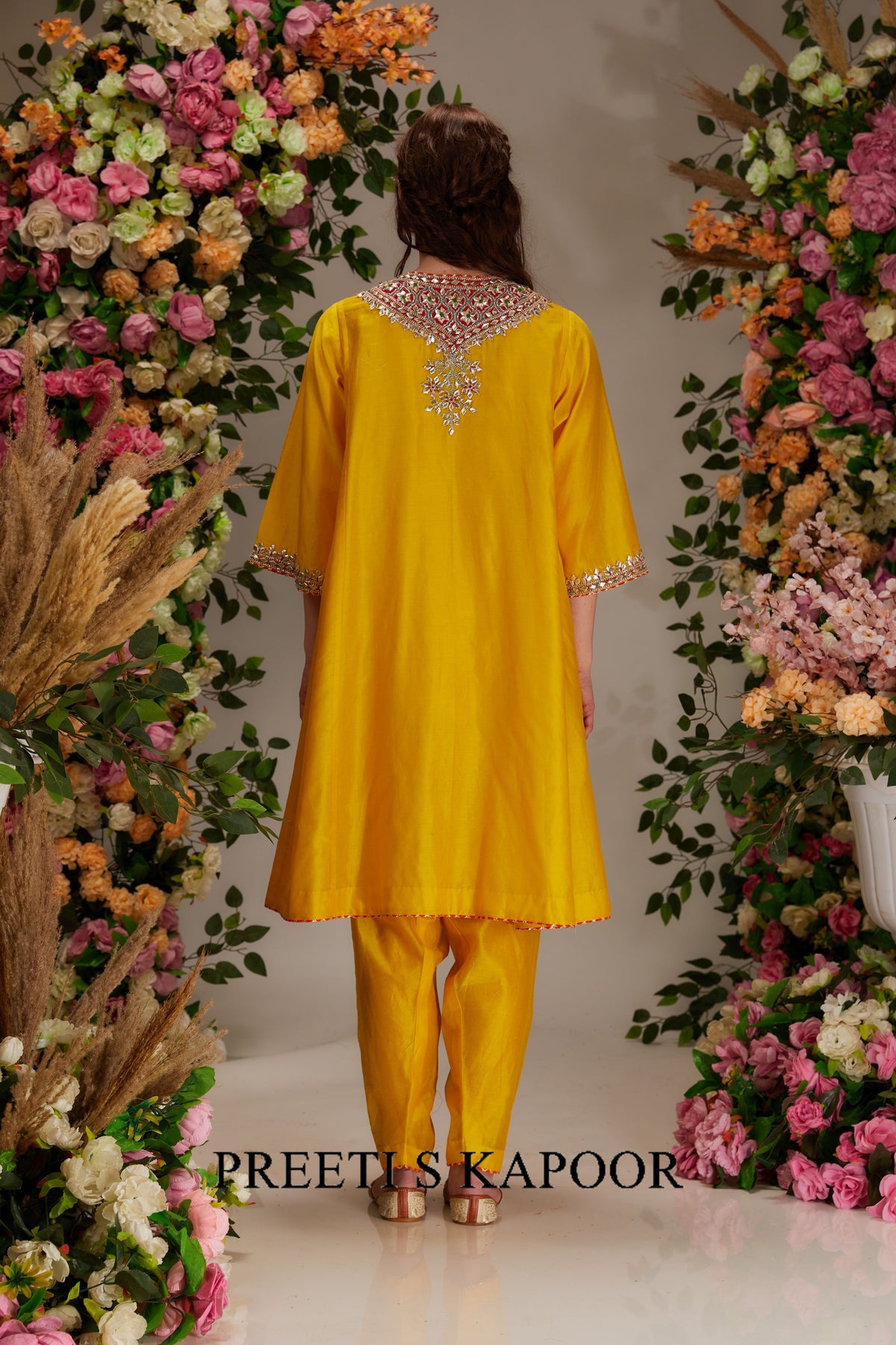 Person wearing a yellow outfit with floral decorations on either side